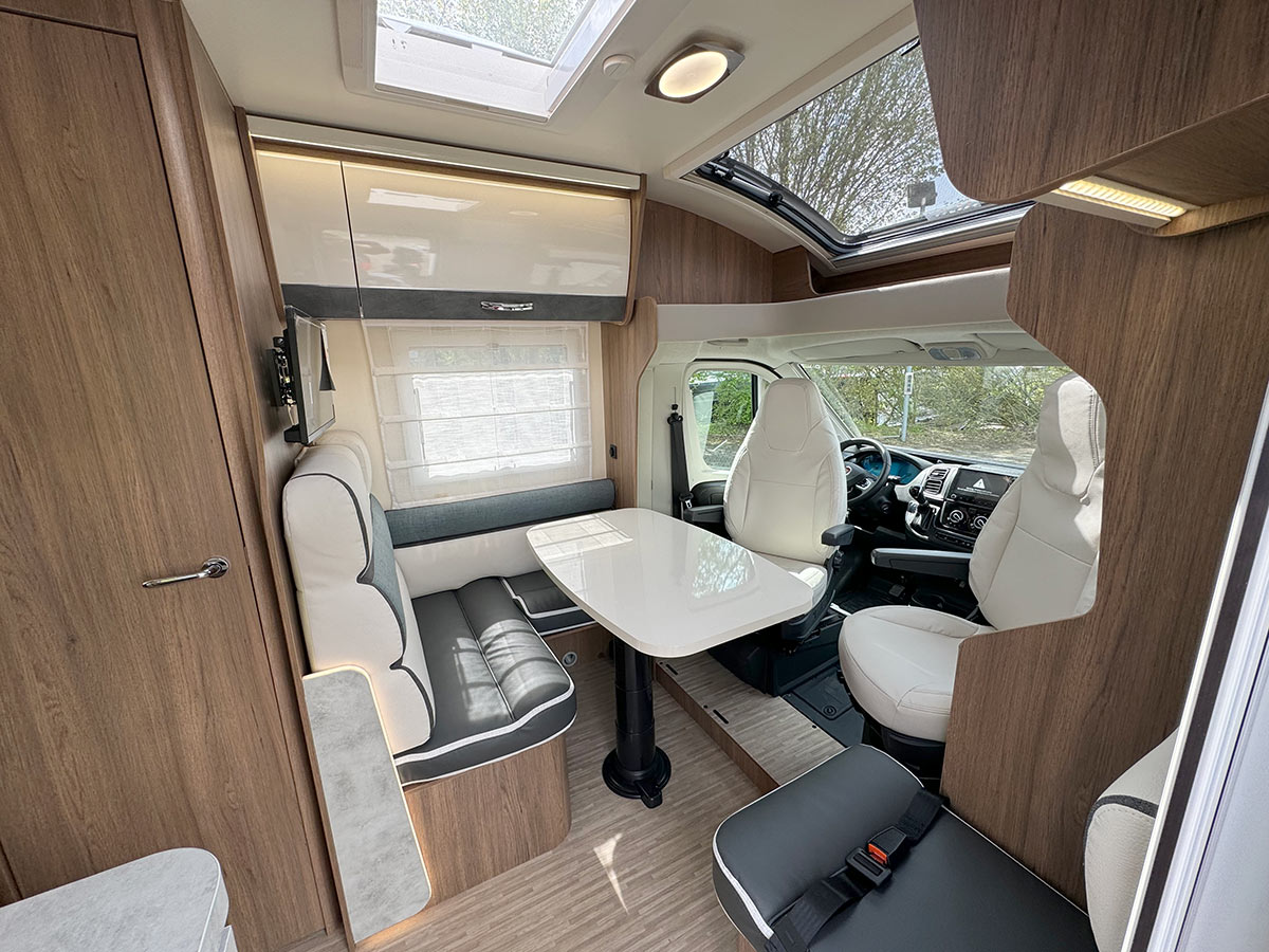 Weiß graues Wohmobil, teilintegriert, Hintergrund bil toscanische landschaft mit eiben und gras, text im foto begleite und in die toscana